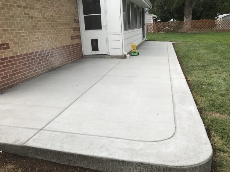 Broom-finished concrete patio along the back of a brick home