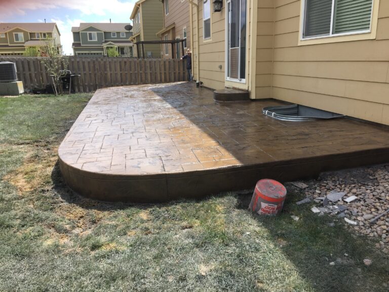 Stamped concrete patio with a curved edge behind a home