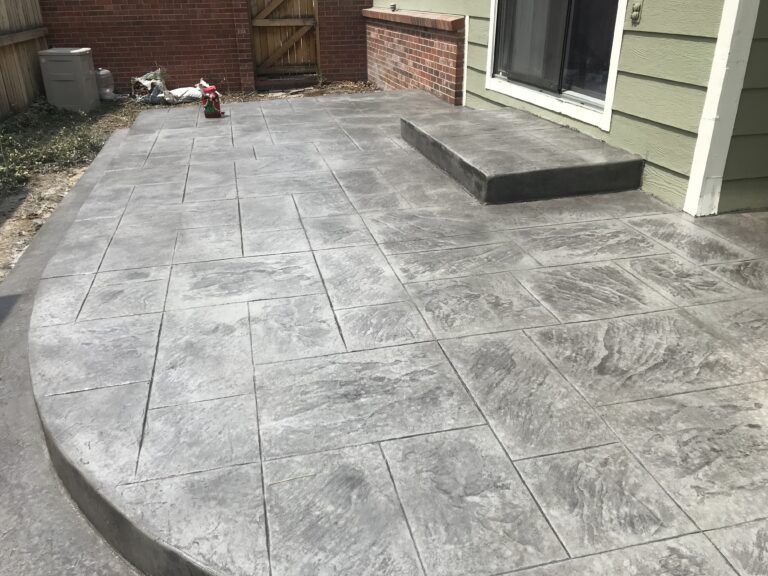 Gray stamped concrete patio with a step up to the house