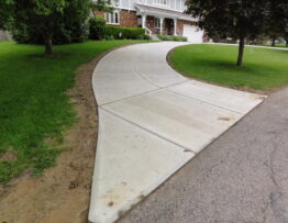 Curved concrete driveway replacement beside a lawn