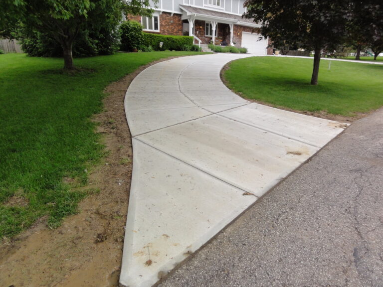 Curved concrete driveway replacement beside a lawn