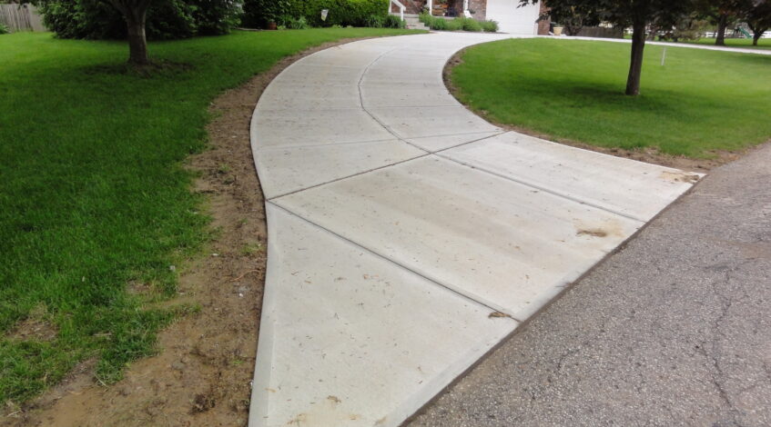 Curved concrete driveway replacement beside a lawn