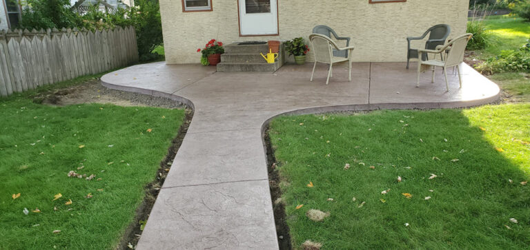 Stamped concrete patio with a curved walkway leading to the back steps